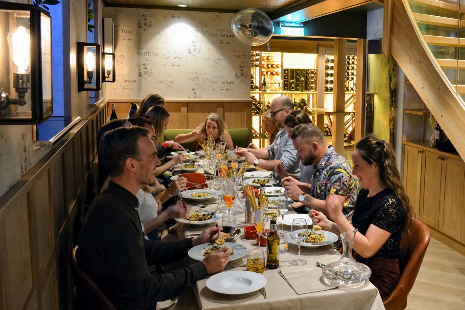 Selskap rundt ett langt bord i underetasjen, med trappen og vinkjelleren bak